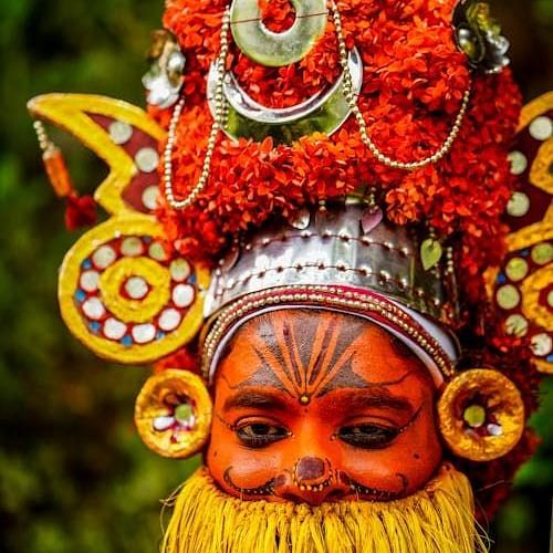 A man wearing the traditional headdress of Onapottan participates in the Onam festival celebrations.