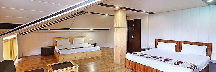 A room at DLS Hotel Devlok, Manali with a sloping roof line alongside a sofa chair and a coffee table