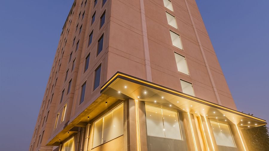 A well lit building of Clarks Inn Suites Jaipur, Ajmer Road with warm lights under a clear sky during early evening