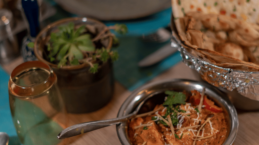 A dining table at BluSalzz Escapade Resort, Lansdowne, is set with bowls of food, flatbread in a basket, a plate, and cutlery.