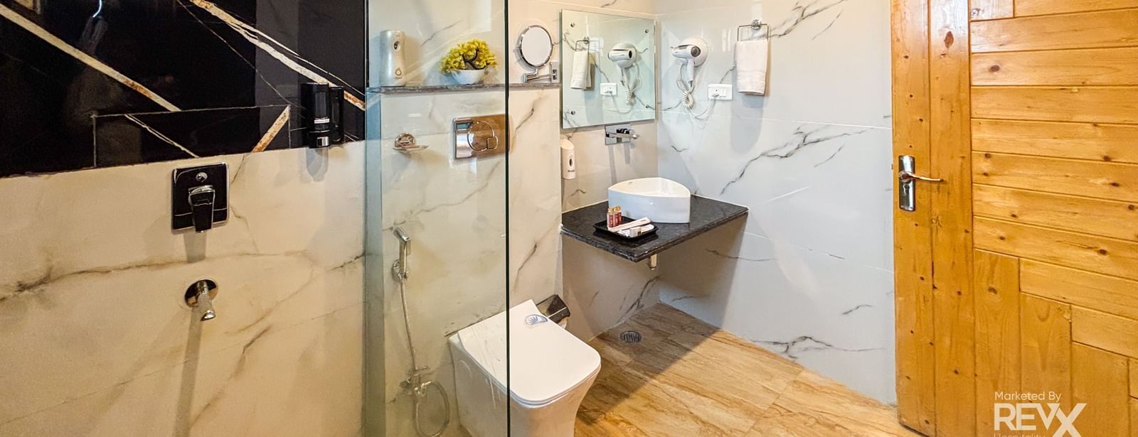 Modern bathroom with glass shower enclosure and premium fittings at Corbett Nirvana Resort.