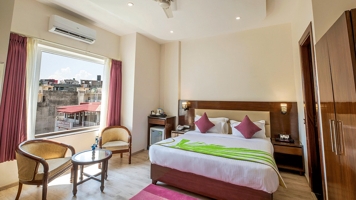 Full view shot of the Deluxe room featuring a double bed along with beautiful city views from the window at Regenta Inn DLS.