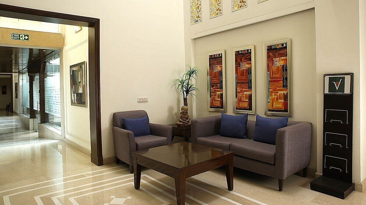 An image of a seating area in a lobby with sofa set and a centre table