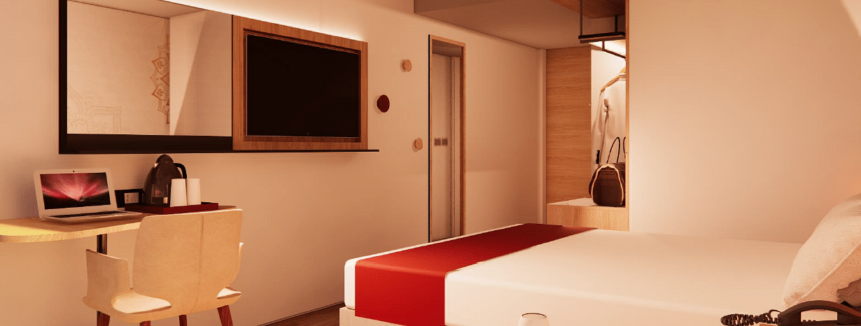 A close up shot of a room at TGI Oberon, Koramangala, highlighting a bed, flat screen TV, a work desk, a chair, and a tea coffee maker