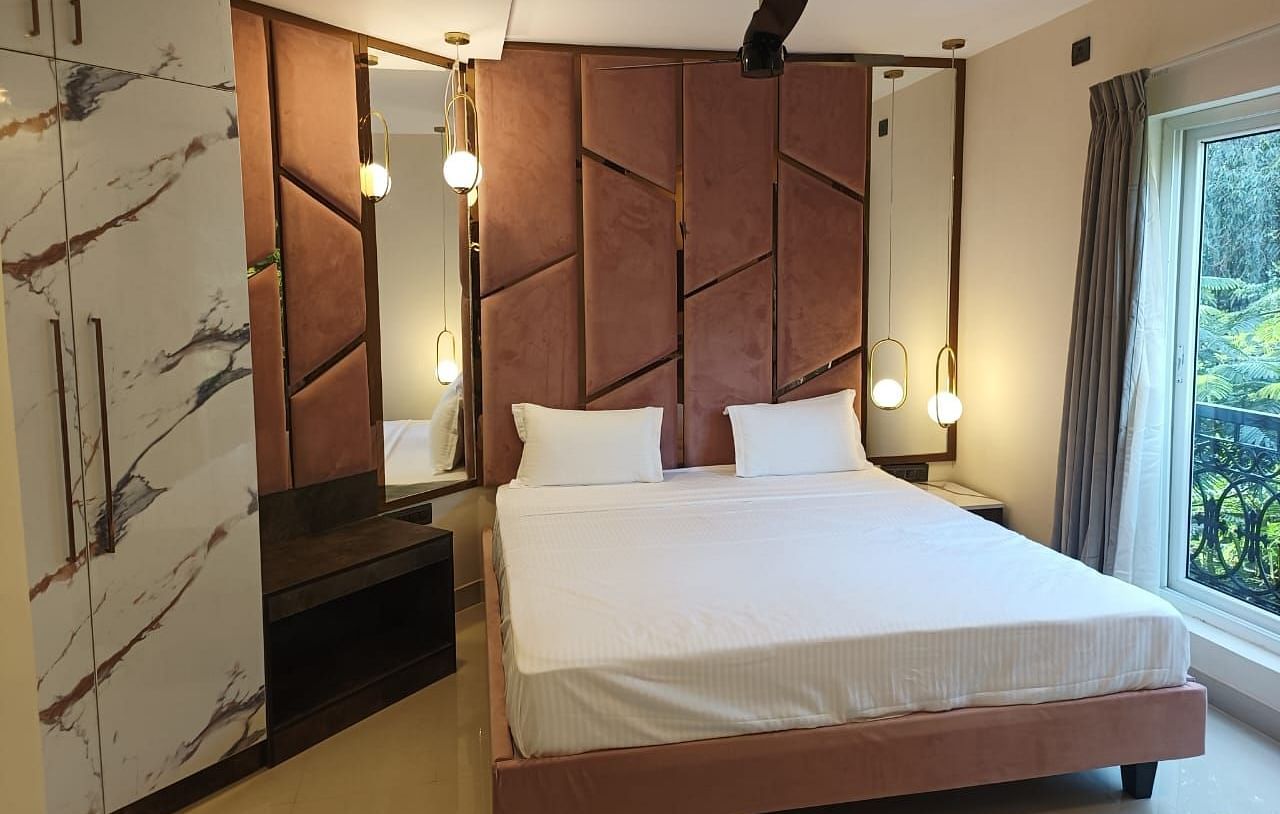 a premium room with a double bed with modern and elegant furnishings and warm lights - Astra Hotels and Suites, Koramangala