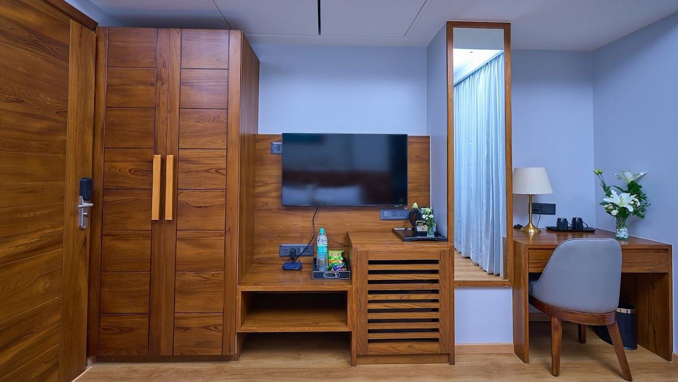 Image of cupboards, dressing table, television and a chair in a room at Visthara - Urban Boutique Hotel, Bangalore