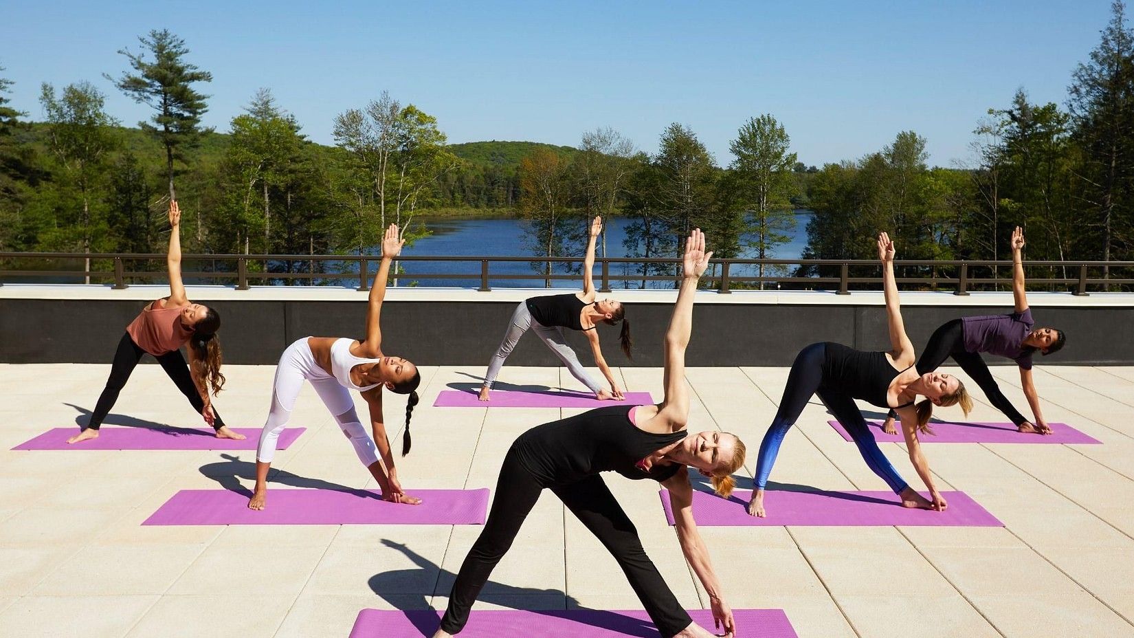 Group of people practising yoga on a rooftop with scenic views at YO1 Health Resort, Catskills, New York.
