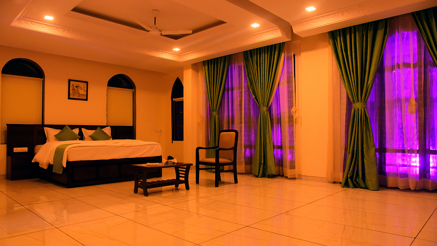 A dimly lit bedroom with large windows and a comfy bed adjacent to the wall - VITS ExcellenSea, Dapoli