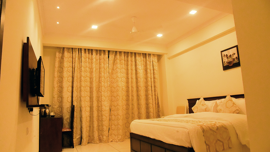 A side view of a bedroom shows the off-white interiors and the TV on the wall - VITS ExcellenSea, Dapoli