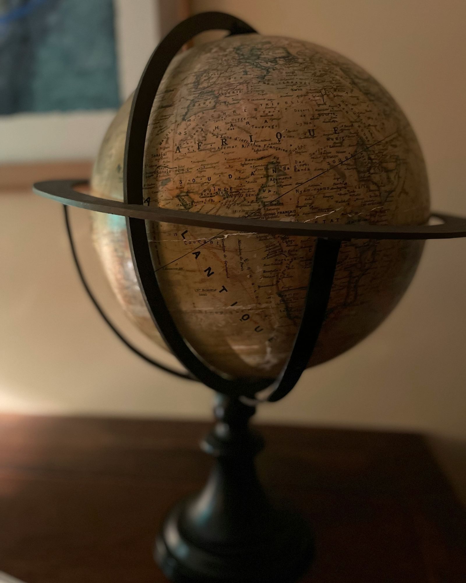 A terrestrial globe on a stand rests on a surface in a softly lit indoor setting.