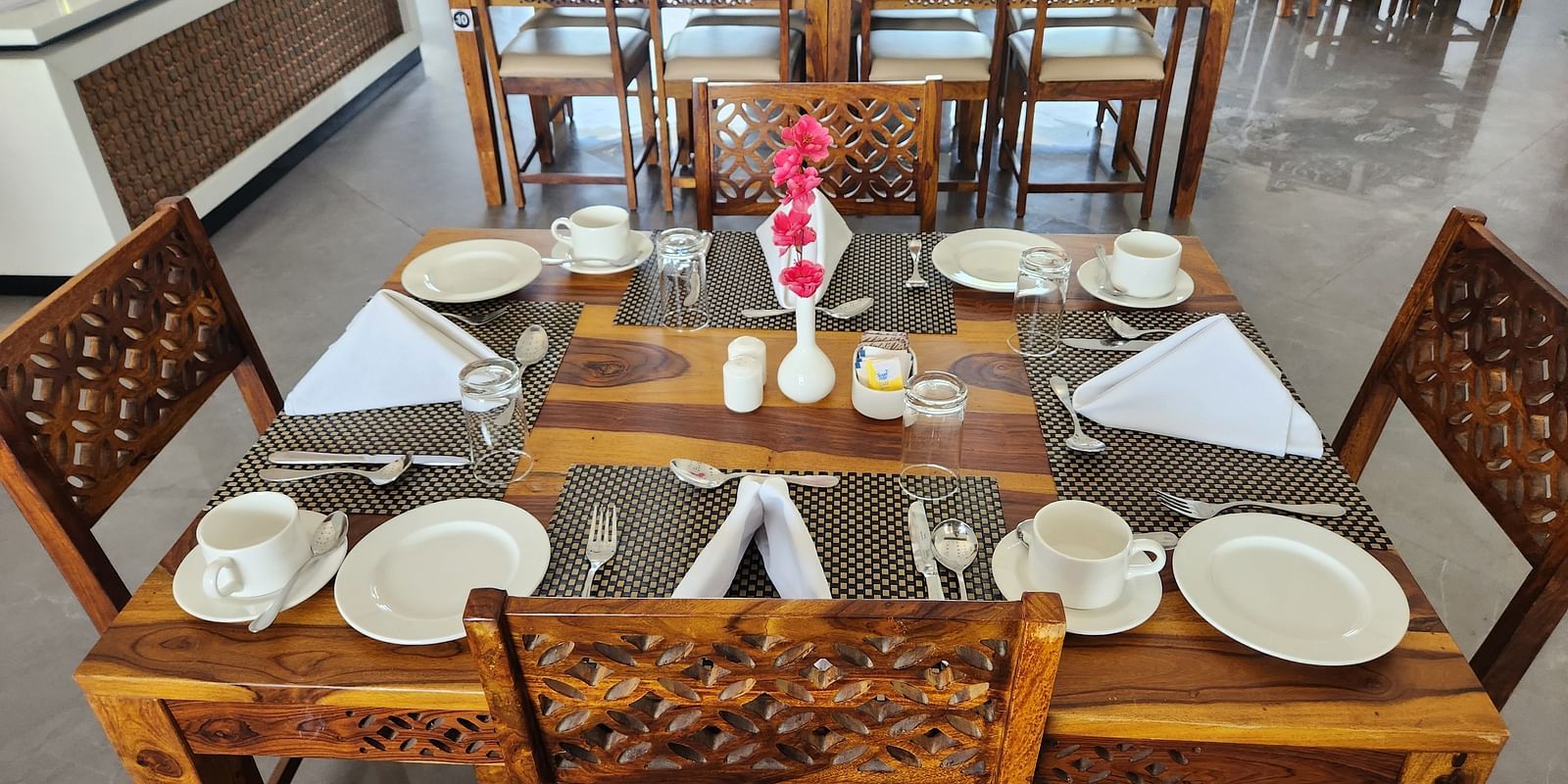 An aerial view of an indoor dining table set with plates and cutlery at the Bamboo Saa Mulberry Resort, Pushkar.