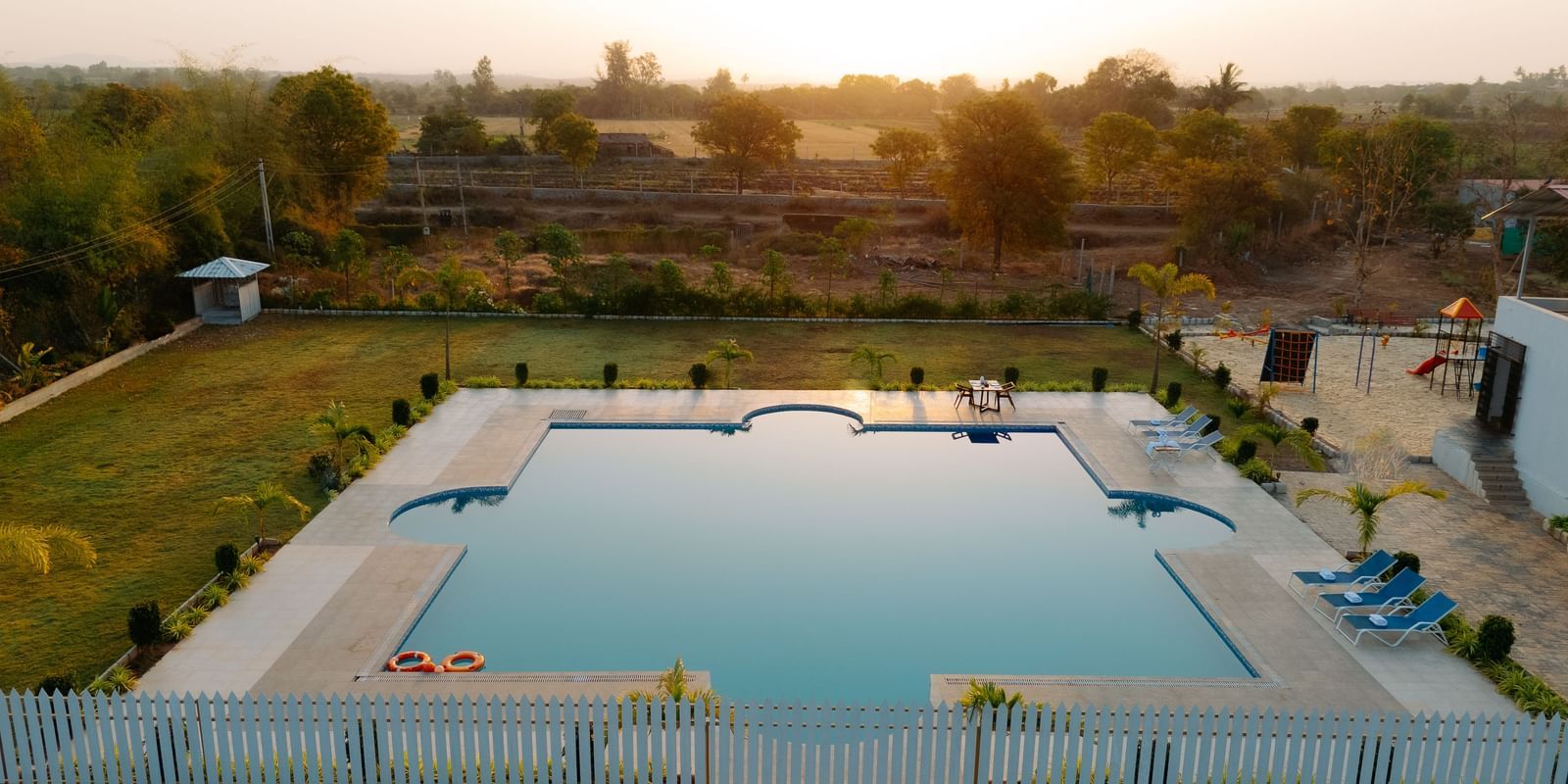 An aerial shot of the swimming pool at the resort with greenery all around | Daksh Eden Greenz