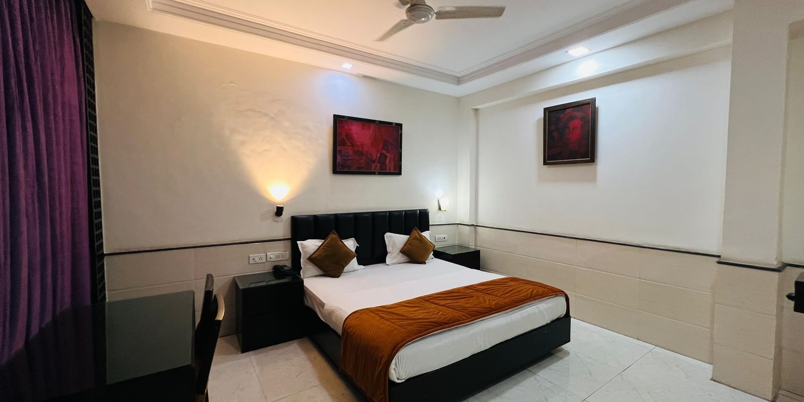 Hotel room featuring a comfortable bed, bedside table, and curtains | Deluxe Room | Hotel Aadhar