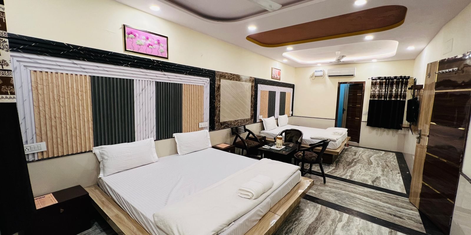 A large hotel room with two beds, a sofa, and modern decor, providing ample space for guests. | Family Room | Hotel City Palace DX