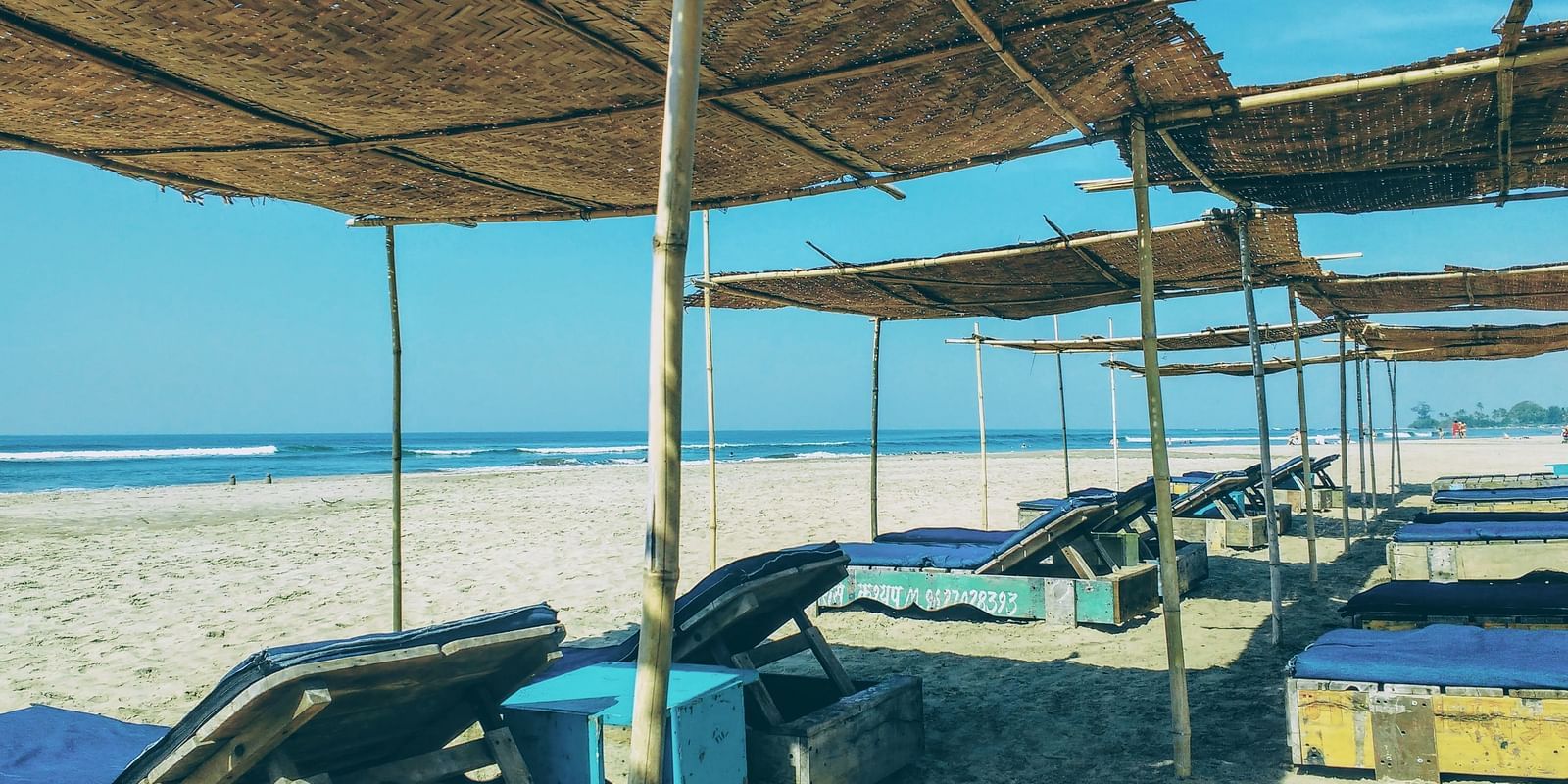 A series of shaded lounge chairs on a sunny beach, perfect for relaxing and enjoying the ocean view.