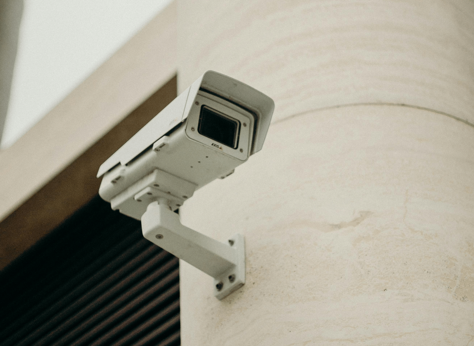A close-up shot of a CCTV camera attached to a concrete pillar.