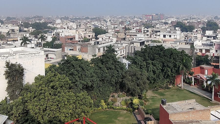 The lawn at Hotel Gold, Panipat with a crowded city landscpae beyong the lush green trees of the lawn.
