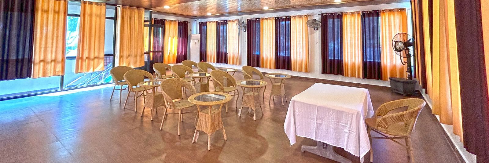 A conference hall with ambient lighting and chairs facing a white table at DLS MJ River Resort, Rishikesh.