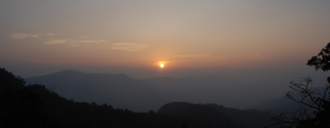 The image shows a sunrise over a mountainous landscape. The mist or fog that lingers in the valleys adds to the mystical and ethereal atmosphere of the image.