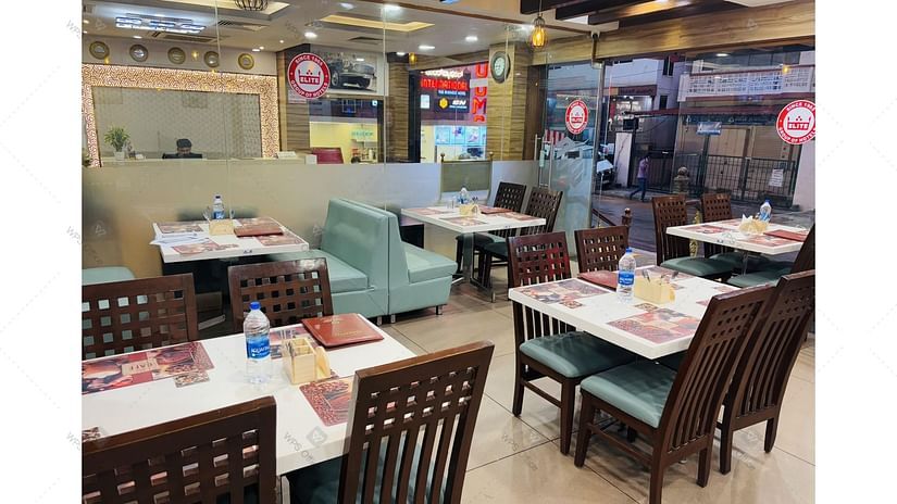Casual dining area with neatly set water bottles, menu card, spoon stand on the table and modern decor at Hotel Dr Rajkumar International restaurant.
