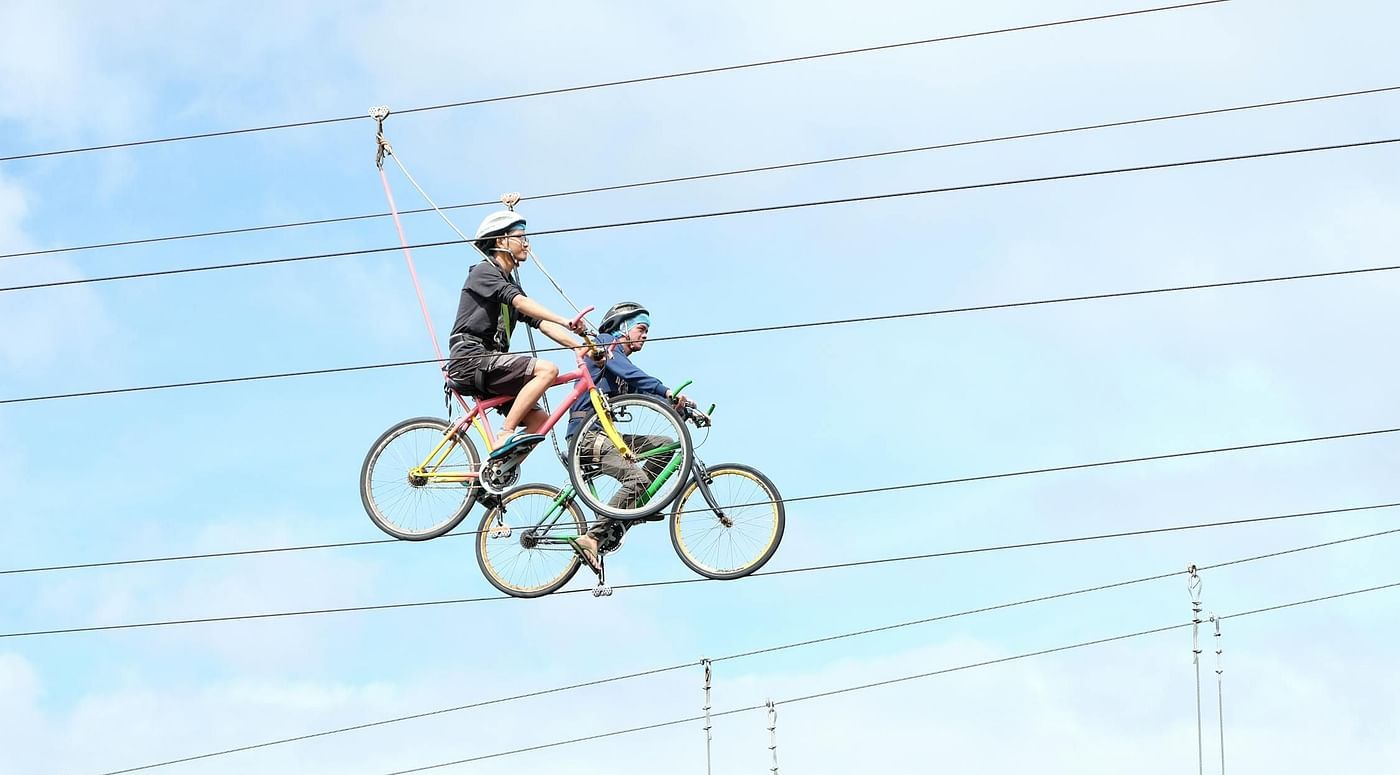 Two people on bicycles on a narrow track high above the ground.