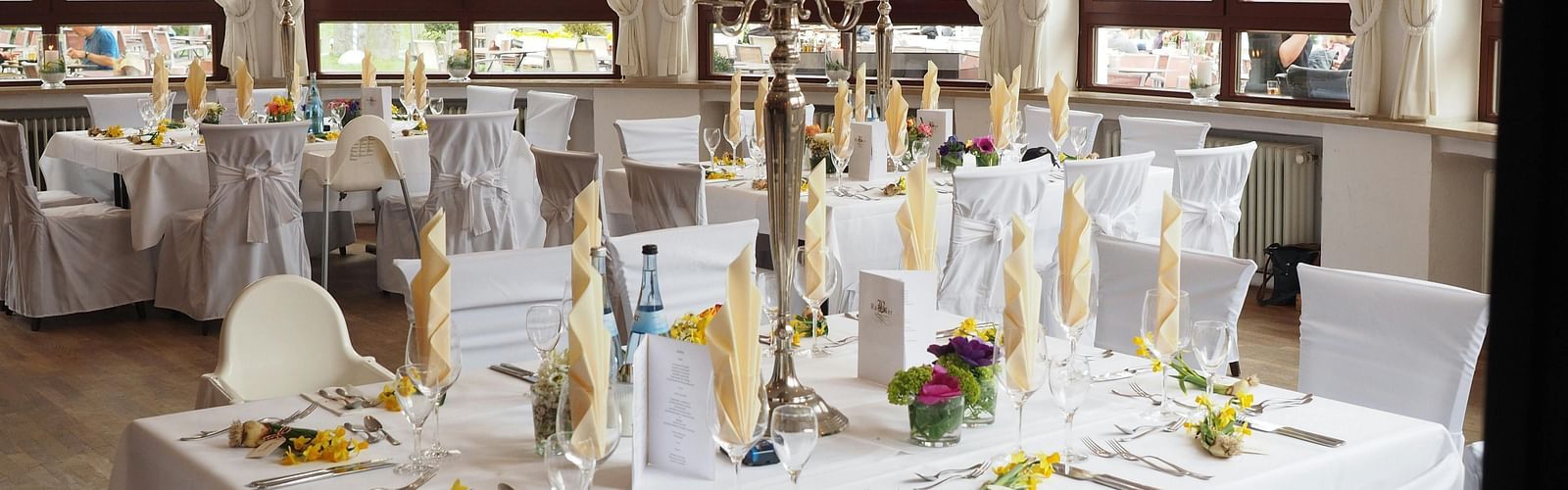A restaurant depicting seating arrangement with cutlery and decorative items on the table