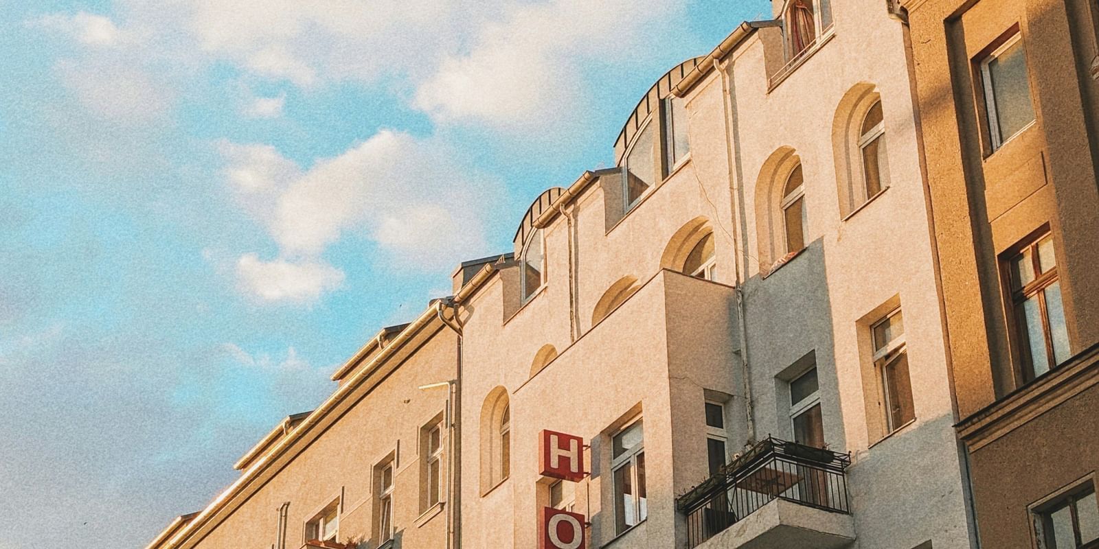  A low-angle view of a row of European-style buildings with balconies under a blue sky