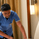 Staff member making a bed with white and teal linen at Featherlite Evoma Hotel, carefully tucking in the corners of the sheet neatly.