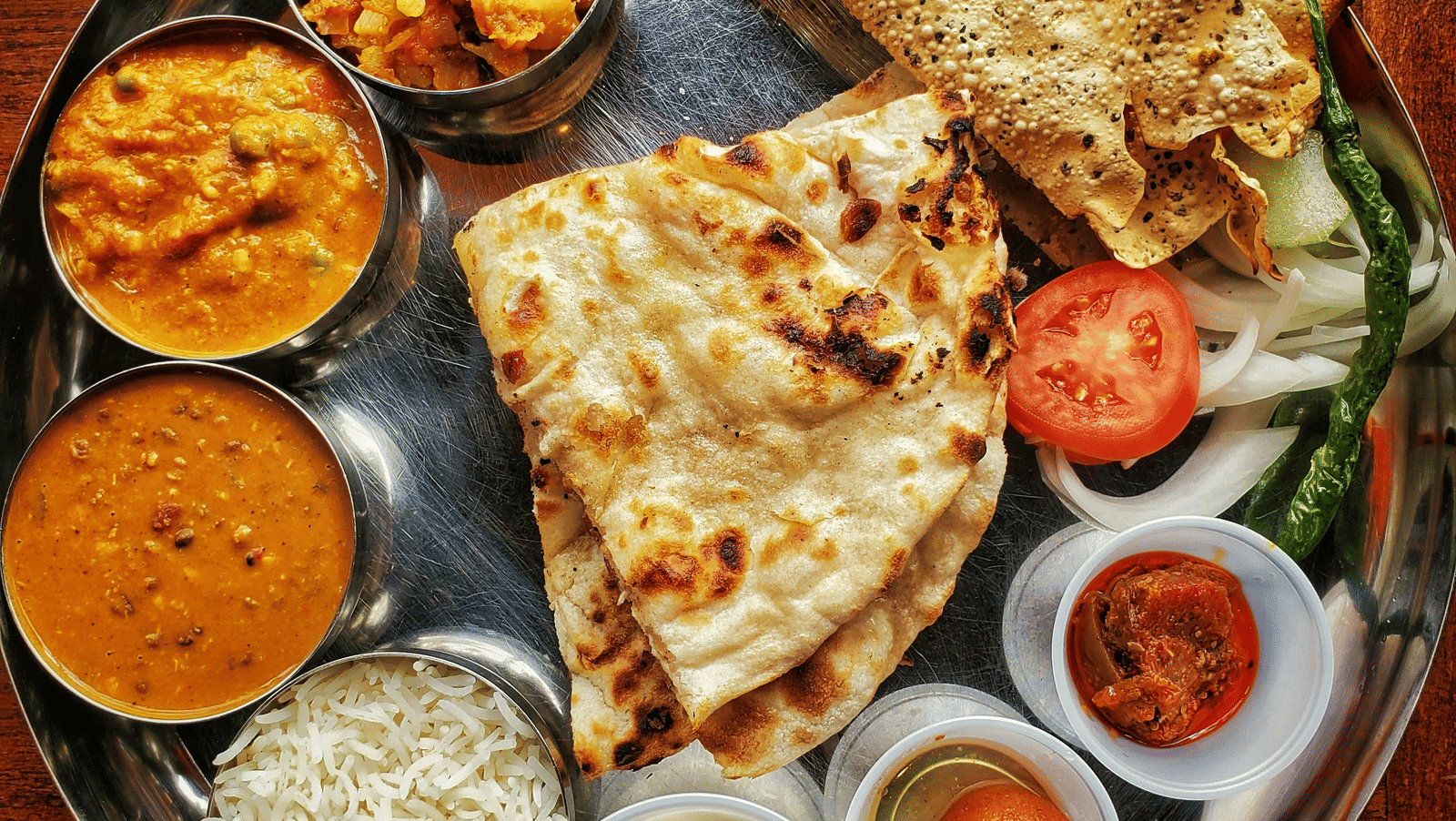 A neatly arranged plate with several Indian delicacies served.