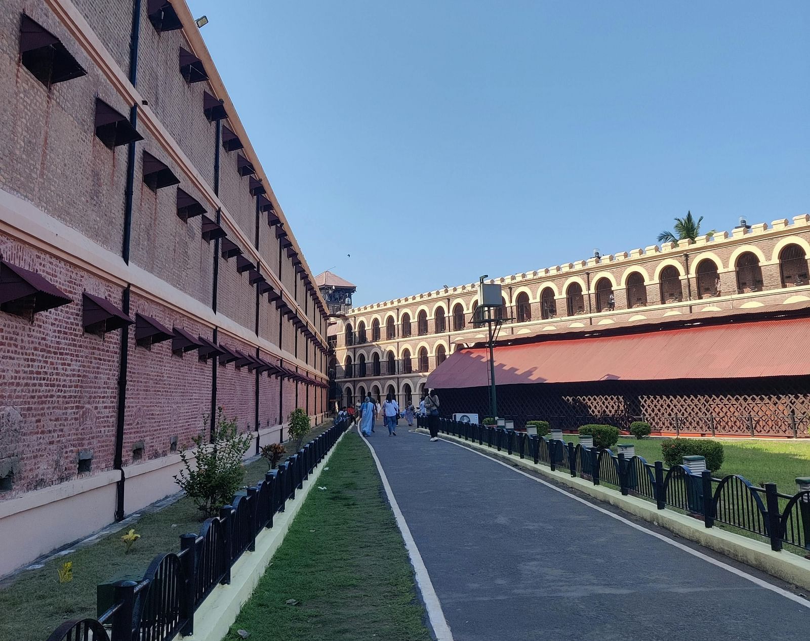  A long, historical red-brick building with arched windows, stands under a clear blue sky.