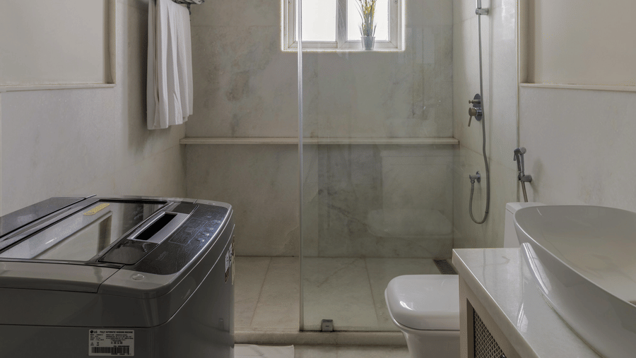 Bathroom with a built-in bathtub, wash basin, ceiling fan, and a window with natural light at Barwara Kothi, Jaipur.