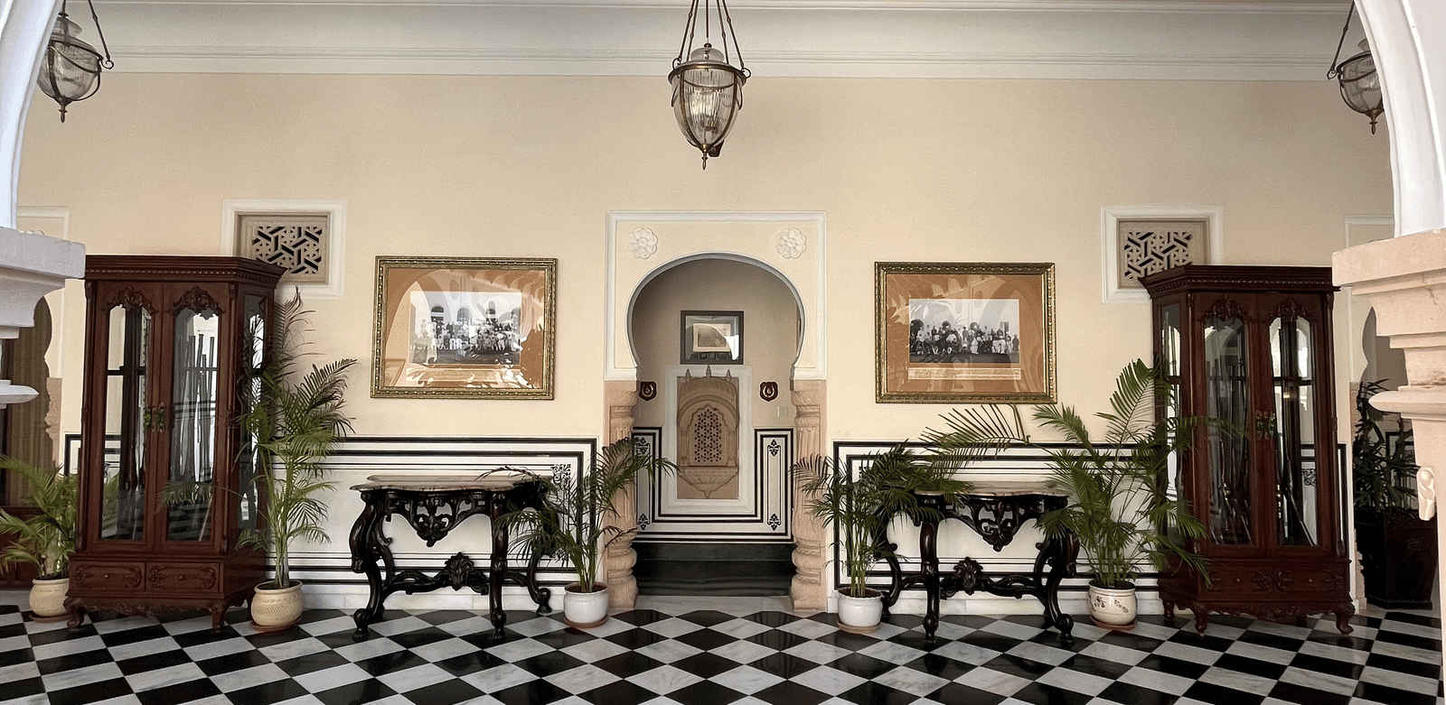 A grand hallway with a black and white tiled floor leading to an arched opening - Khas Bagh, Jaipur.
