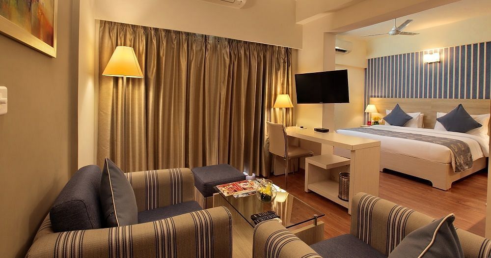 Deluxe room at Starlit Suites, Bangalore with a double bed and sofa seating