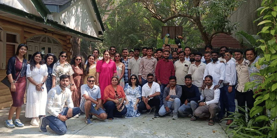 Group photo of people posing outdoors at EsselWorld Bird Park, Mumbai, with trees, greenery, and a signboard in the background.