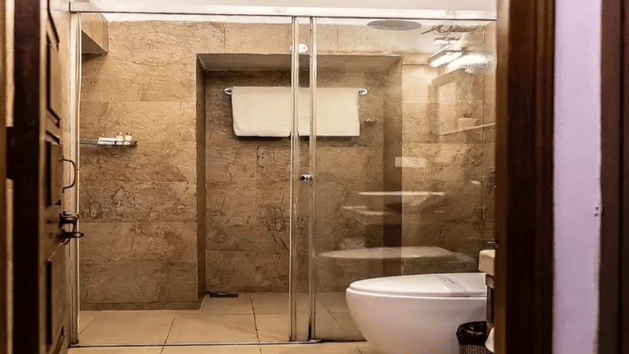  Hotel Devnadi, Haridwar | A bathroom with a toilet seat, a sink, a mirror, and lights.