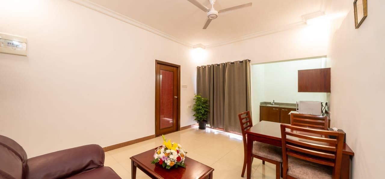 A well arranged living space with a cosy sofa and wooden chairs offers a welcoming area for guests at Lords Midtown Suites.