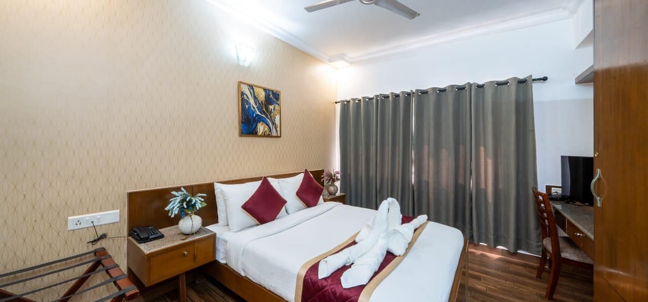 A comfortable bedroom features a neatly made bed with decorative towels and a television for entertainment at Lords Midtown Suites.