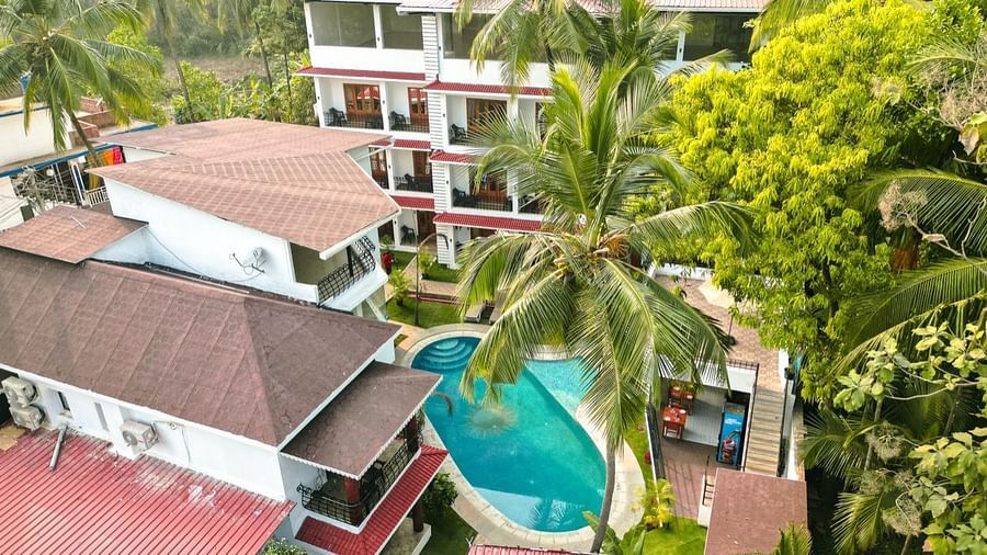 An aerial view of the The Verda de Miranda Resort nestled amidst palm trees, featuring multiple buildings and a turquoise pool.