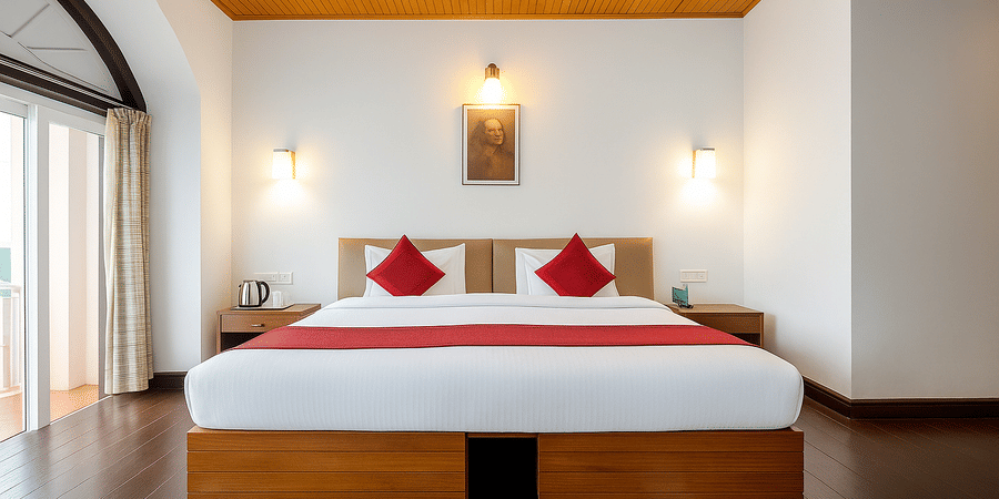 Wide angle view of a room at Central Hotels showing two beds with red and white bedding wooden ceiling vaulted arch white walls and warm wall lamps on both sides.