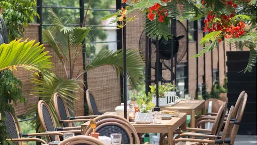 Garden café seating with cane chairs and plants at Polo Floatel Kolkata.