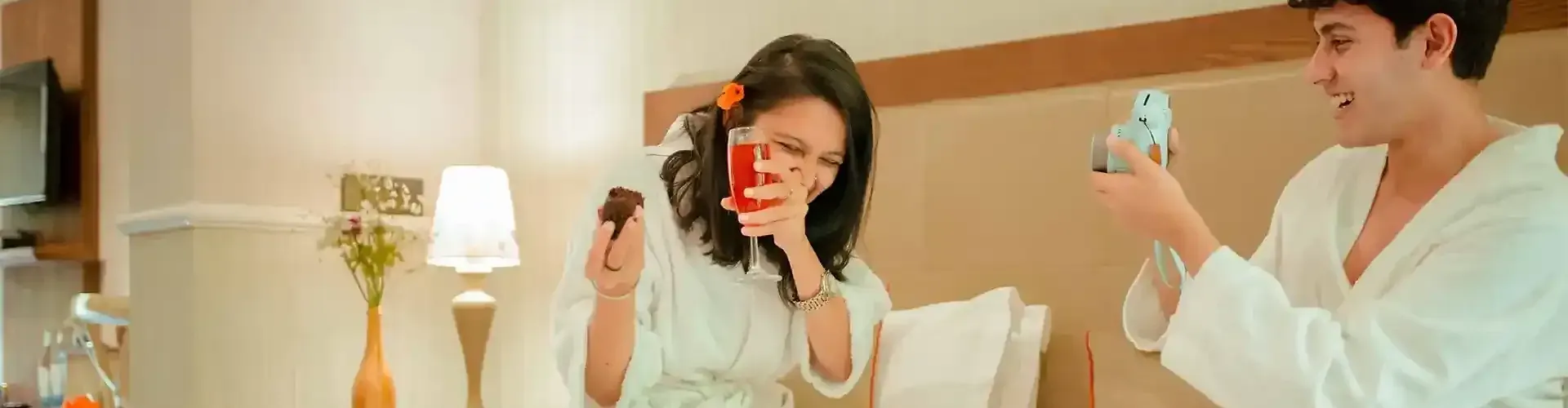 Two people sitting on a bed holding glasses st Karma Chalets.