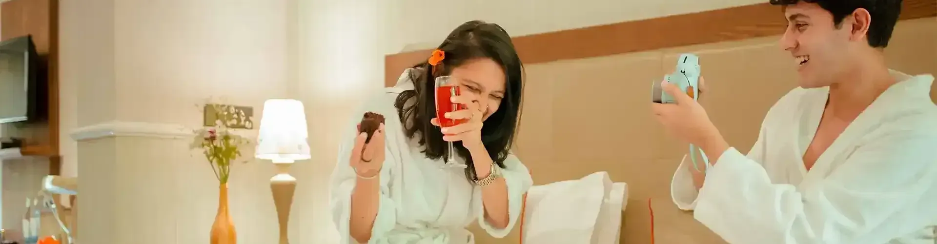 Two people sitting on a bed holding glasses st Karma Chalets.