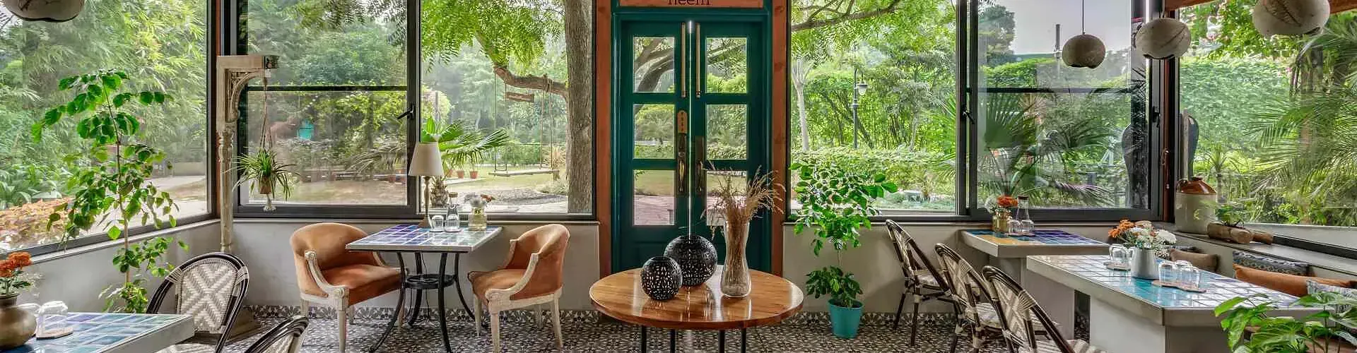 Glass-enclosed café-style seating area with garden views at Karma Chalets.