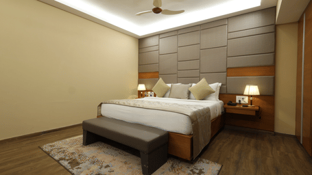 Interiors of a hotel room with a bed, a bed-bench, and a fan at Rang Lords Inn Bharuch