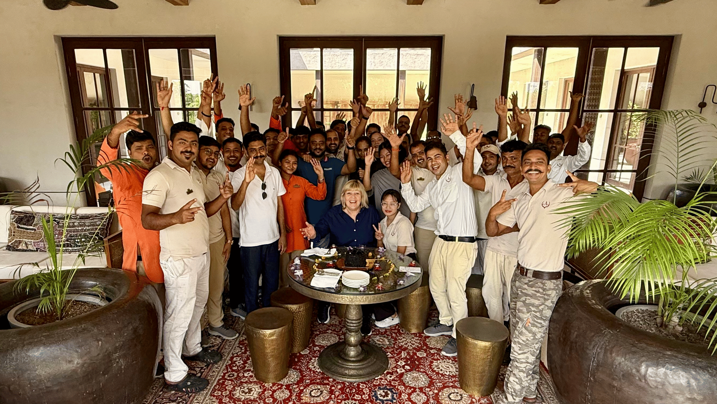 Aramness Gir team members gathered in an indoor lounge, smiling and raising their hands in celebration.