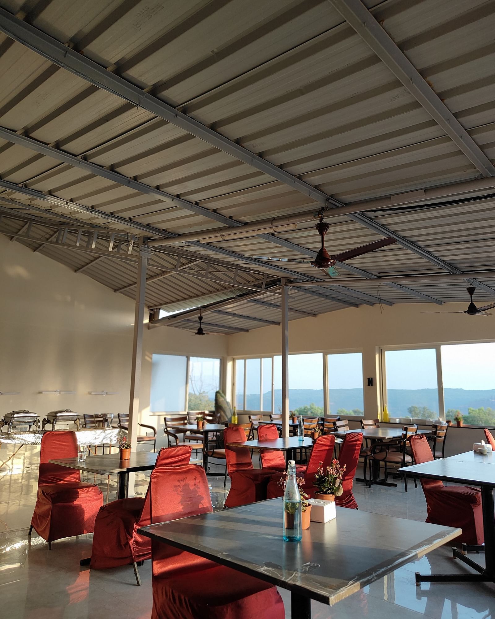 The interior of a dining area with metal beams and red chairs.