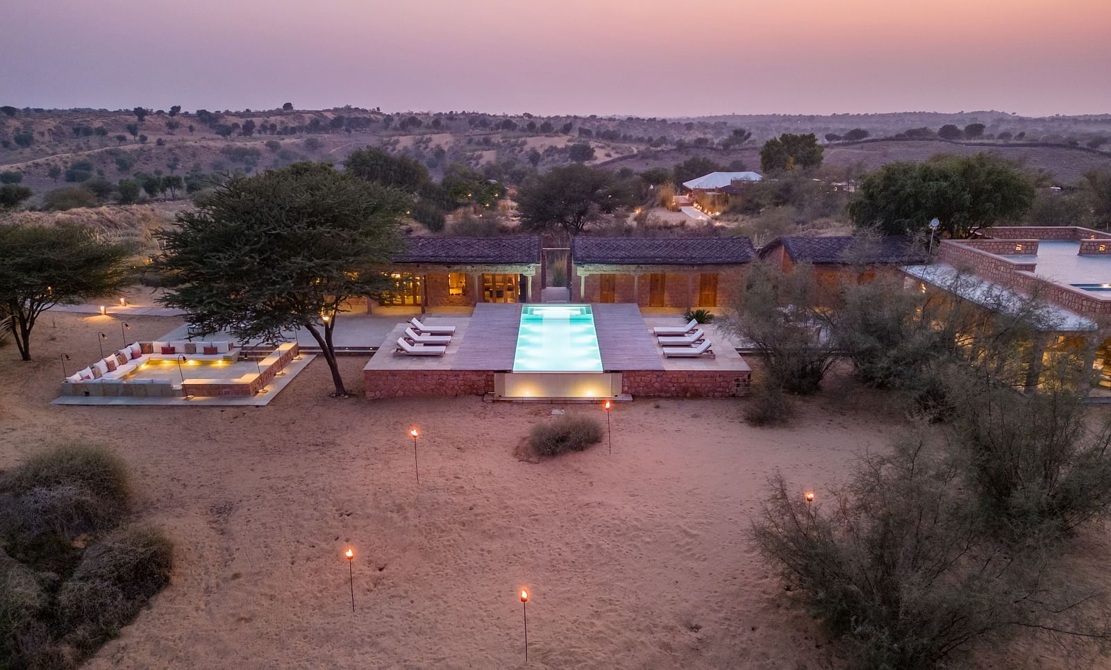 A well-lit path leads to a modern desert villa at twilight, highlighting the blend of luxury and nature - MANVAR Resort & Desert Camp
