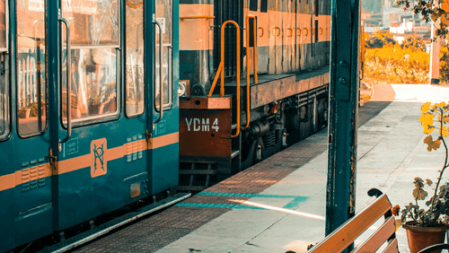 A vintage train at a station platform with wooden benches in the foreground