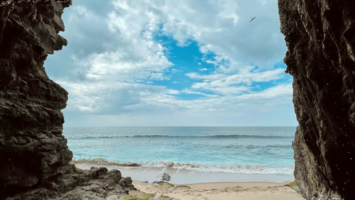 Natural cave located near a clear blue sea