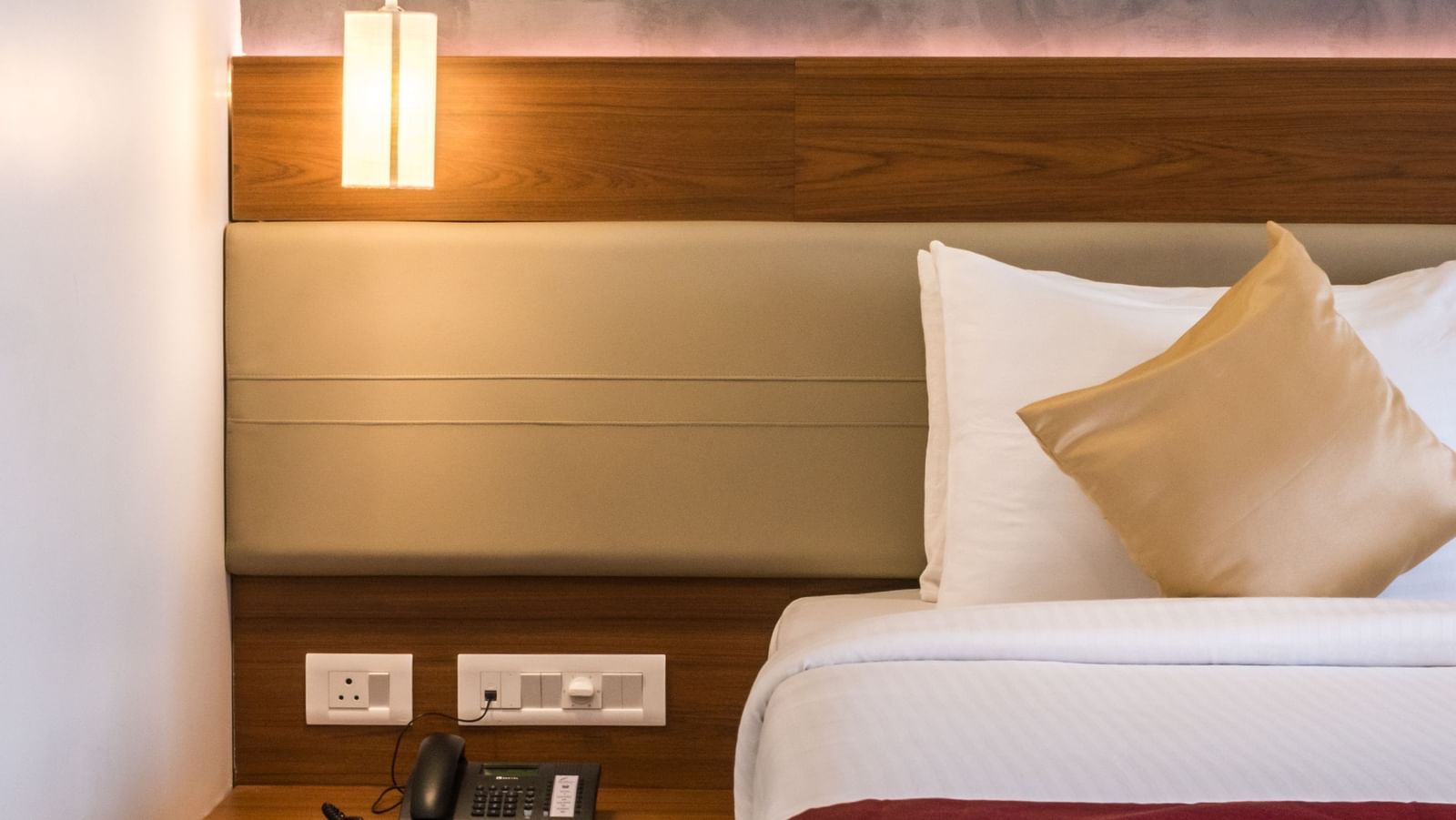 A comfortable hotel bedroom with a large bed, stylish headboard, and bedside table with a lamp at Shilton Dee Cee.